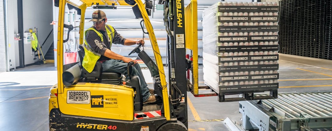 Worker using a forklift truck in a production factory.